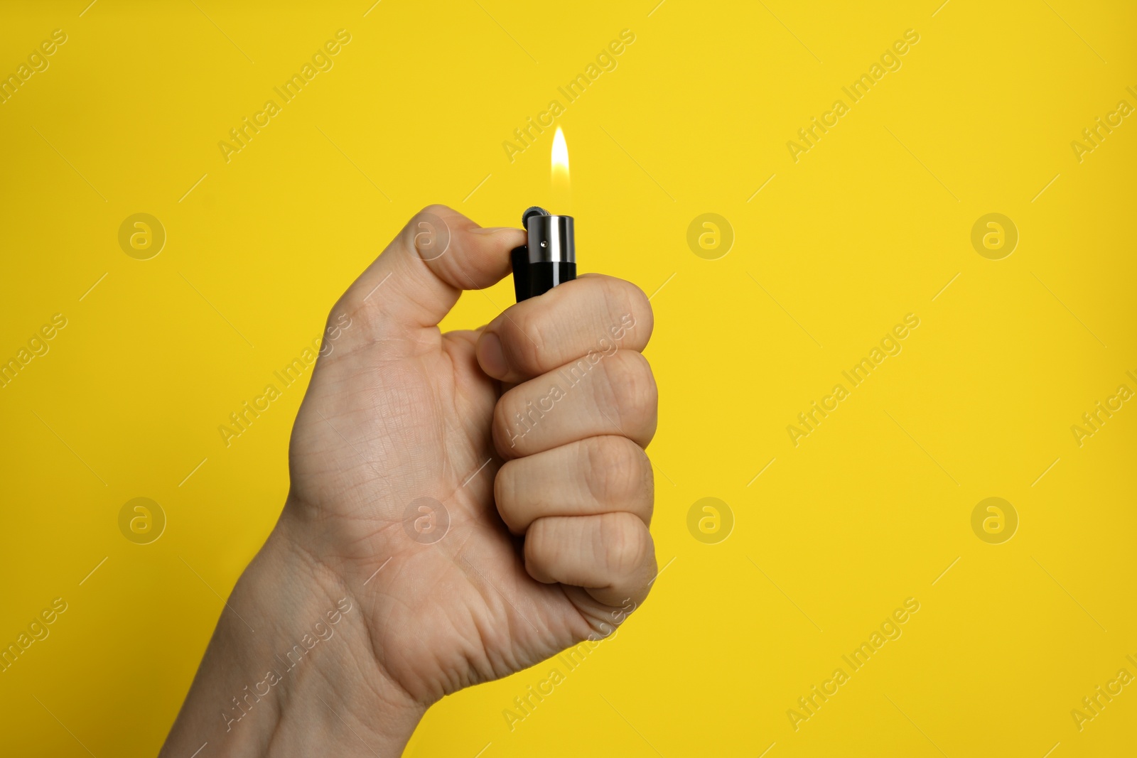 Photo of Man holding lighter on yellow background, closeup. Space for text