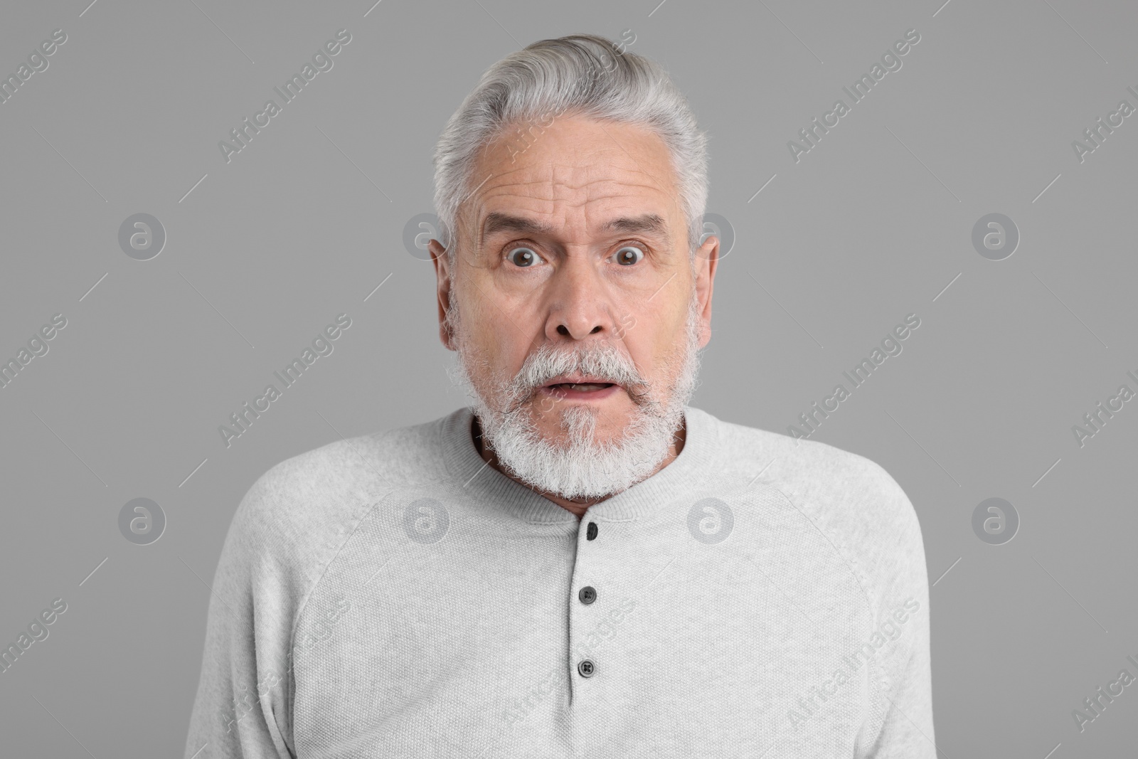 Photo of Portrait of surprised senior man on grey background