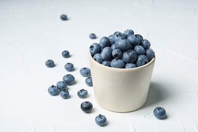 Photo of Crockery with juicy and fresh blueberries on white table