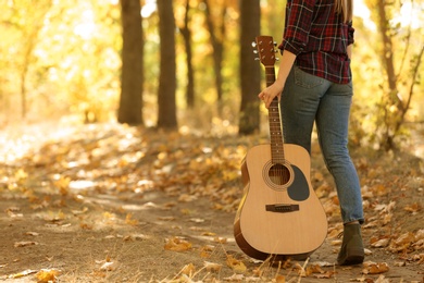 Photo of Teen girl with acoustic guitar in autumn park, closeup