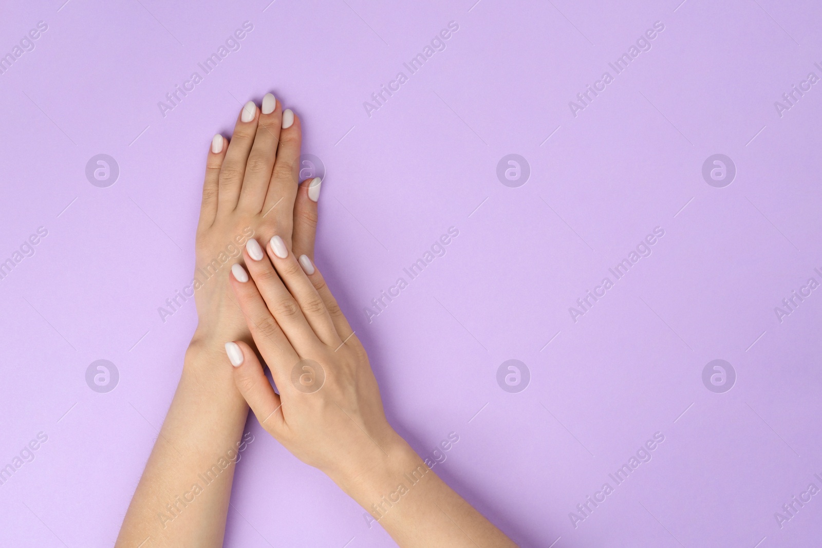 Photo of Woman with white polish on nails against violet background, top view. Space for text