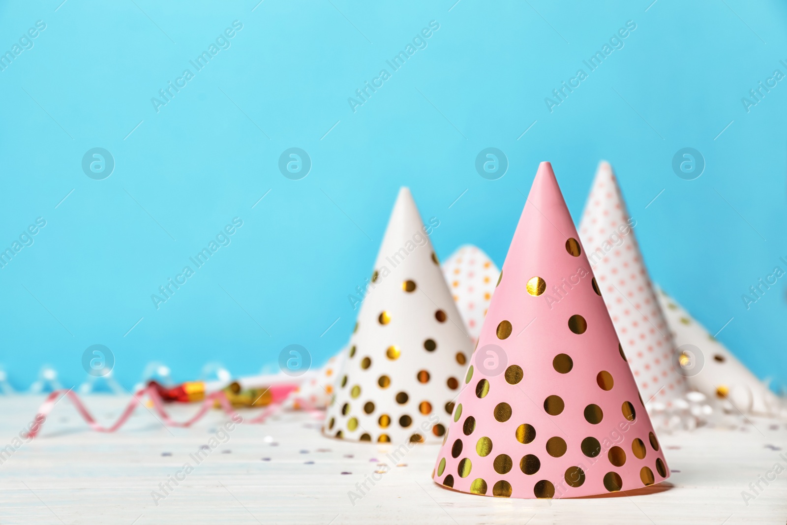 Photo of Birthday party caps on table against color background