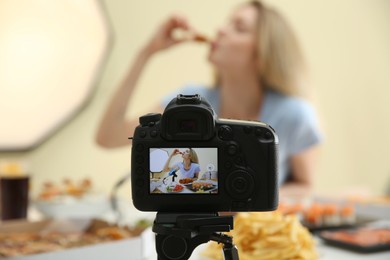 Photo of Food blogger recording eating show against light background, focus on camera screen. Mukbang vlog