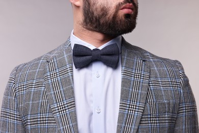 Man in suit, shirt and bow tie on grey background, closeup