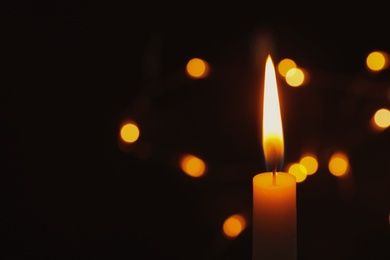 Photo of Wax candle burning on blurred background, closeup