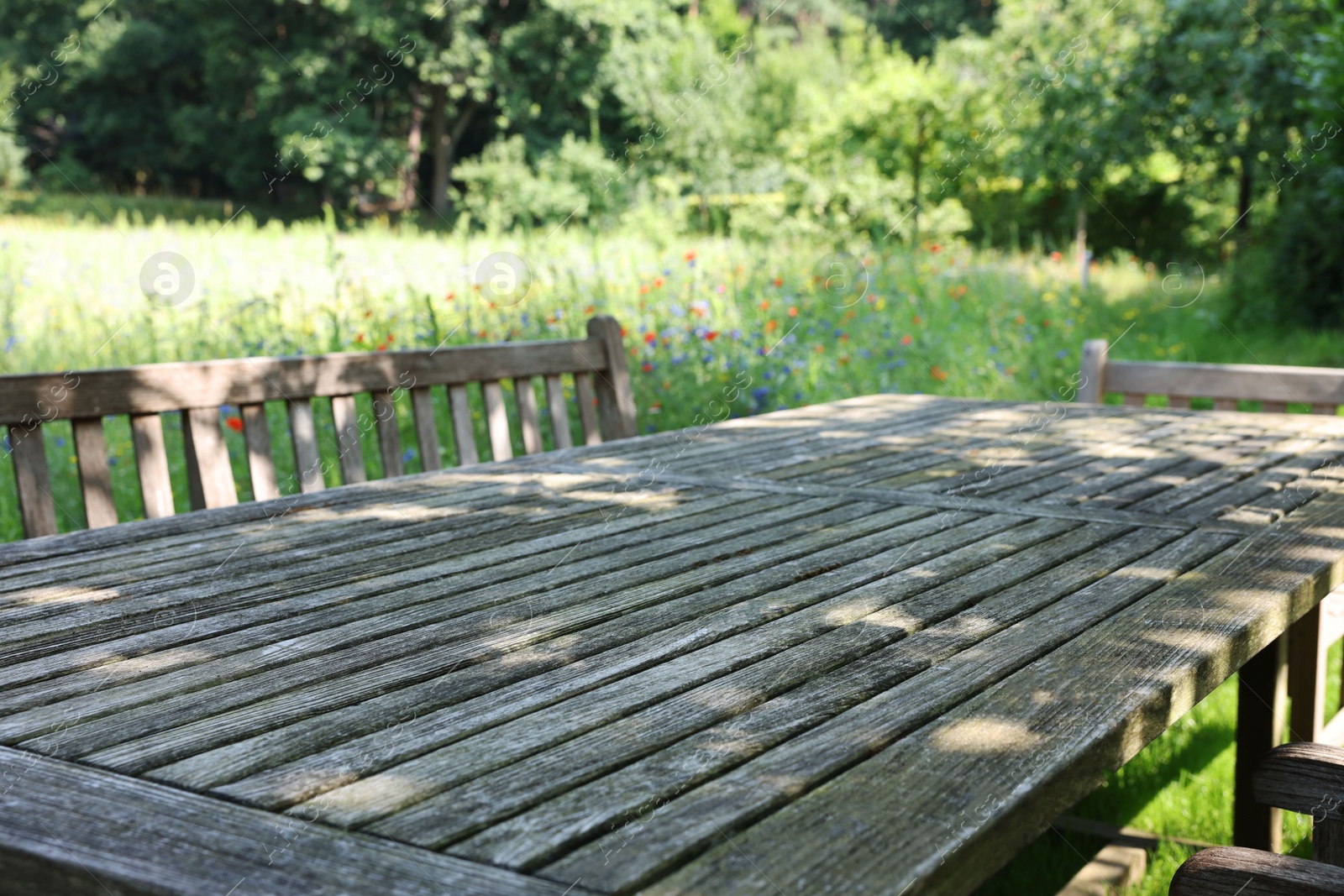 Photo of Empty wooden table with bench on sunny day in garden