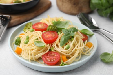 Delicious pasta primavera and cutlery on light gray table, closeup