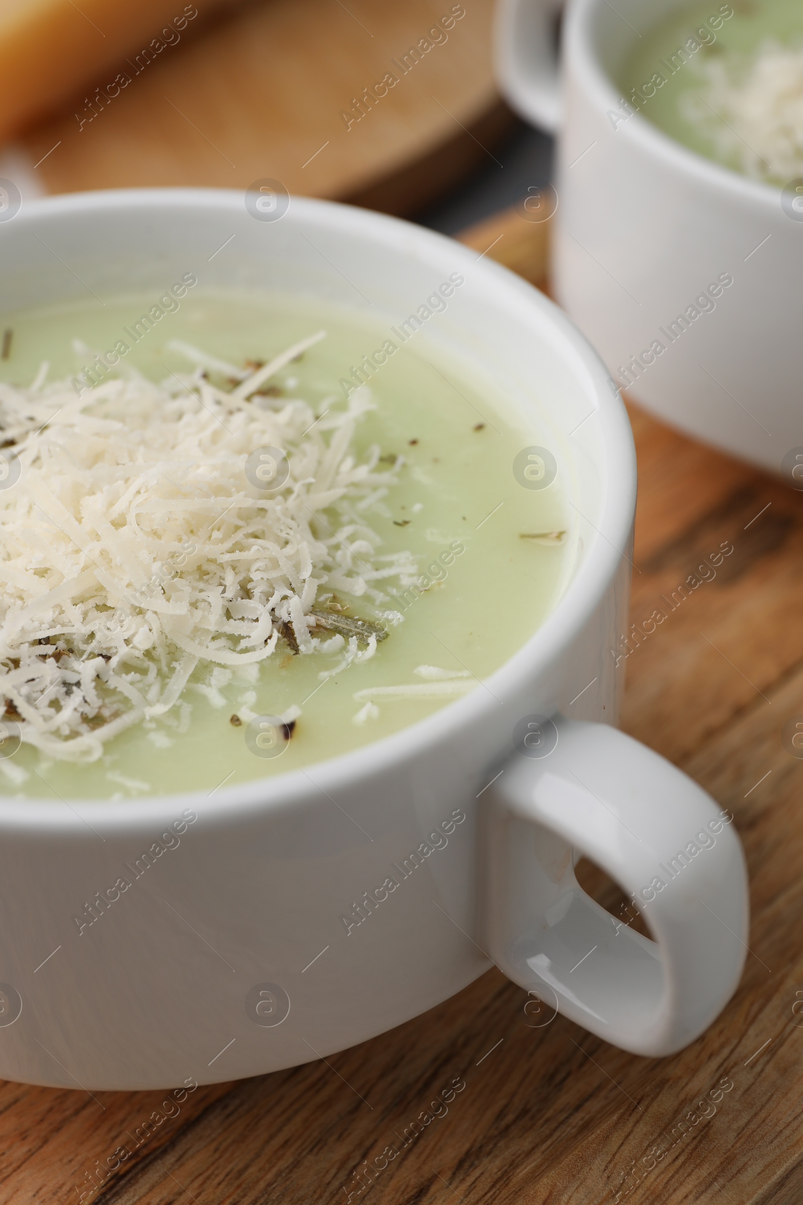 Photo of Delicious cream soup with parmesan cheese in bowls on wooden board, closeup