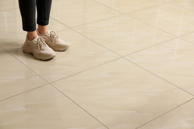 Woman standing on ceramic floor, closeup. Space for text