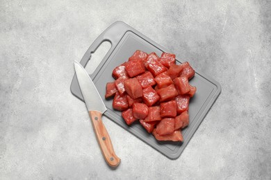 Photo of Cooking delicious goulash. Raw beef meat and knife on light grey table, top view