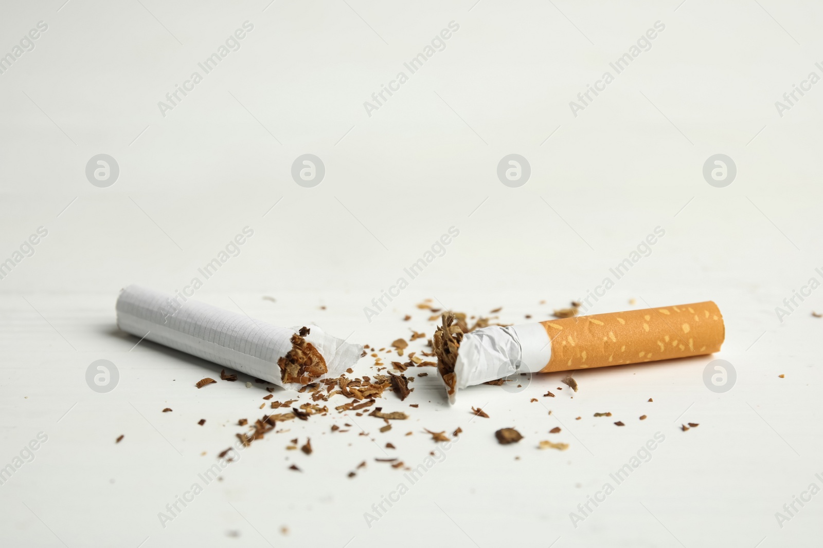 Photo of Broken cigarette on white table, closeup. Quitting smoking concept