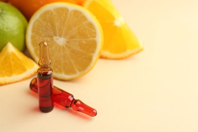 Skincare ampoules with vitamin C, different citrus fruits and leaves on beige background, closeup. Space for text