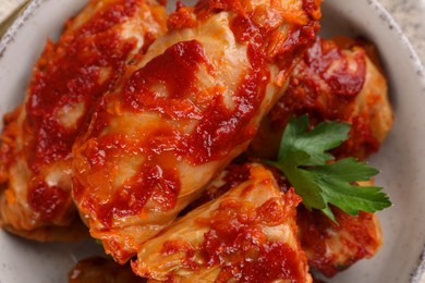 Delicious stuffed cabbage rolls cooked with homemade tomato sauce in bowl, top view