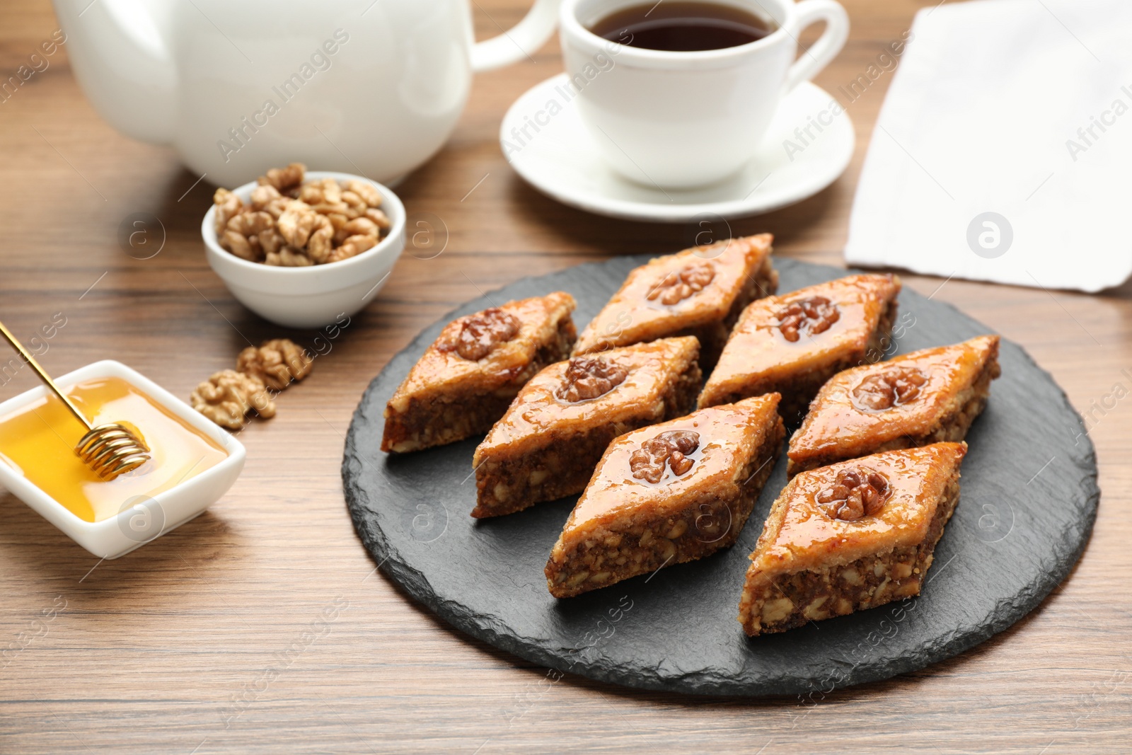 Photo of Delicious sweet baklava with walnuts and honey on wooden table