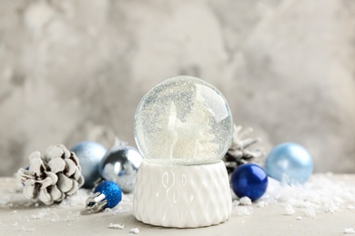 Beautiful snow globe, Christmas balls and pine cone on light table