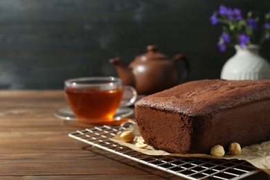 Delicious chocolate sponge cake and nuts on wooden table. Space for text
