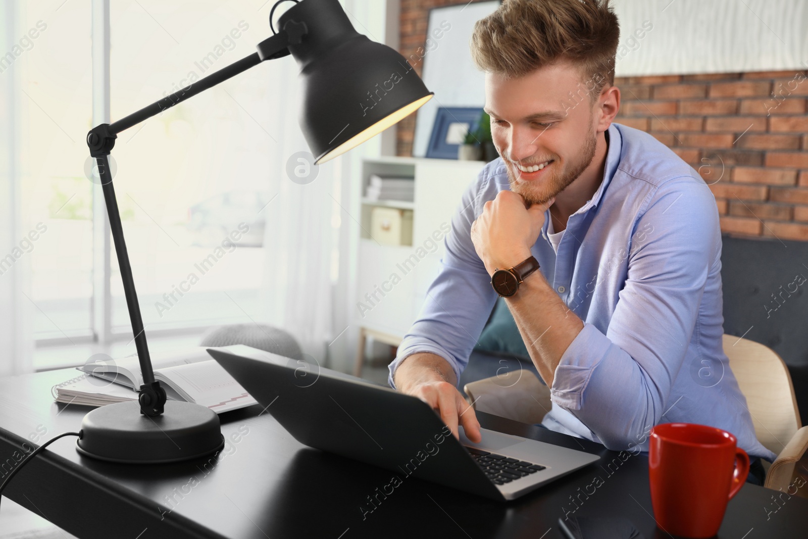 Photo of Young man using laptop at table indoors