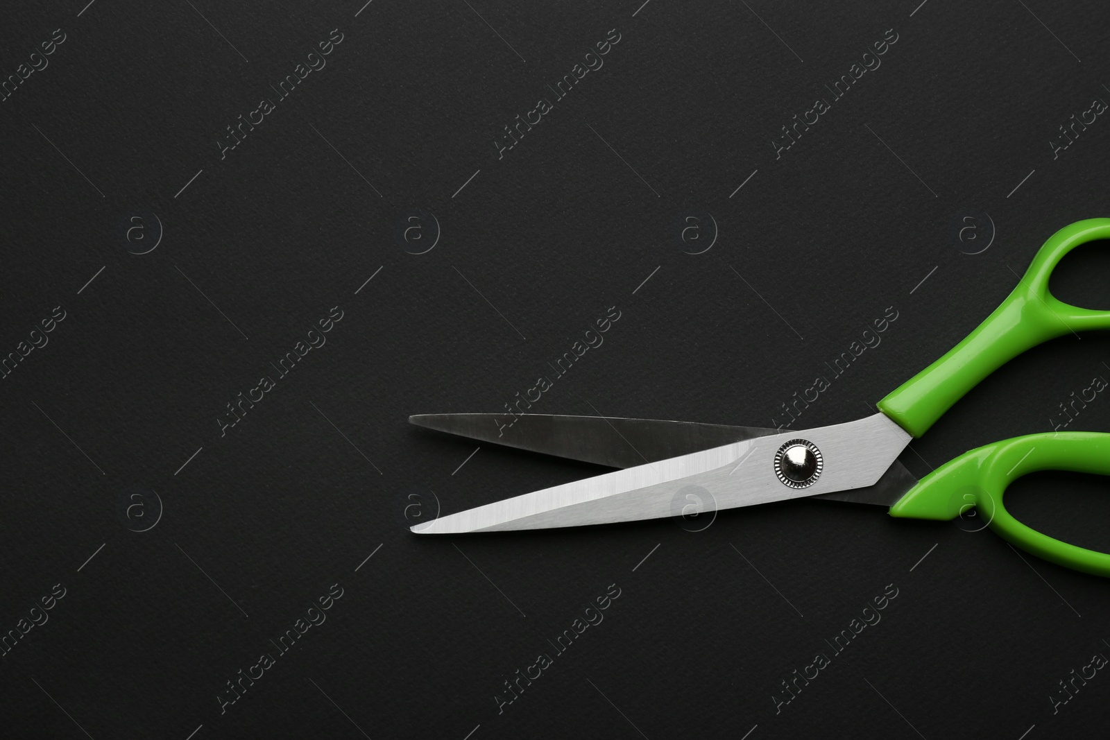 Photo of Pair of sharp scissors on dark background, top view. Space for text