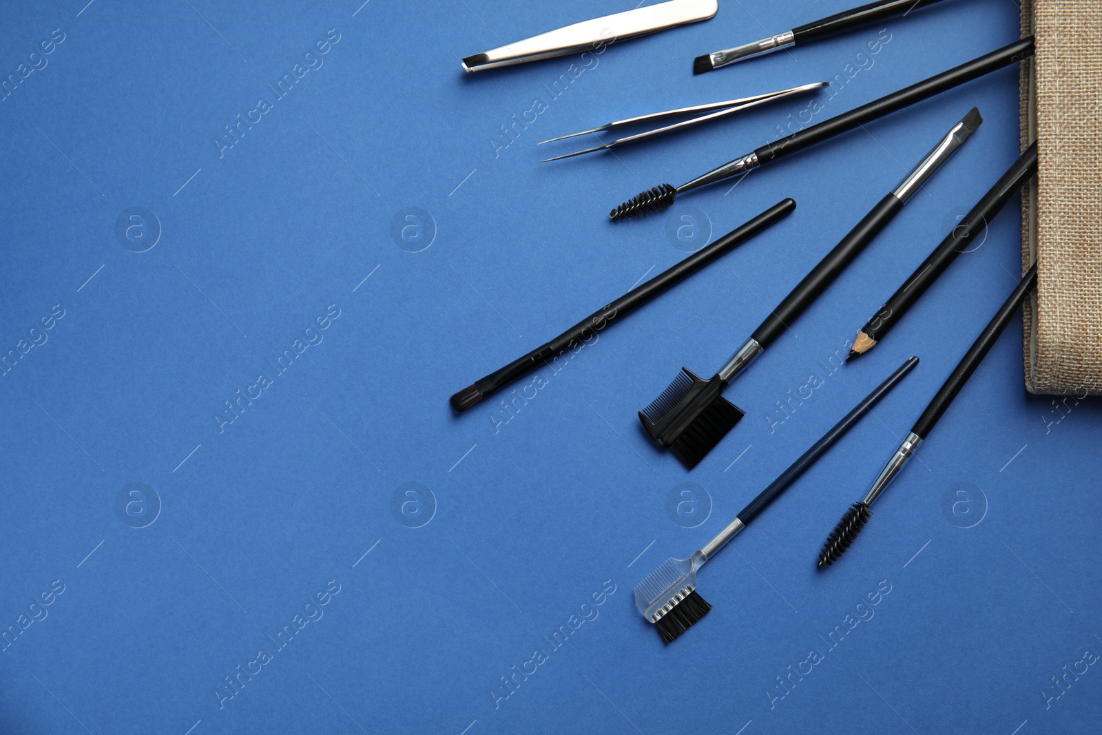 Photo of Set of professional eyebrow tools on blue background, flat lay. Space for text