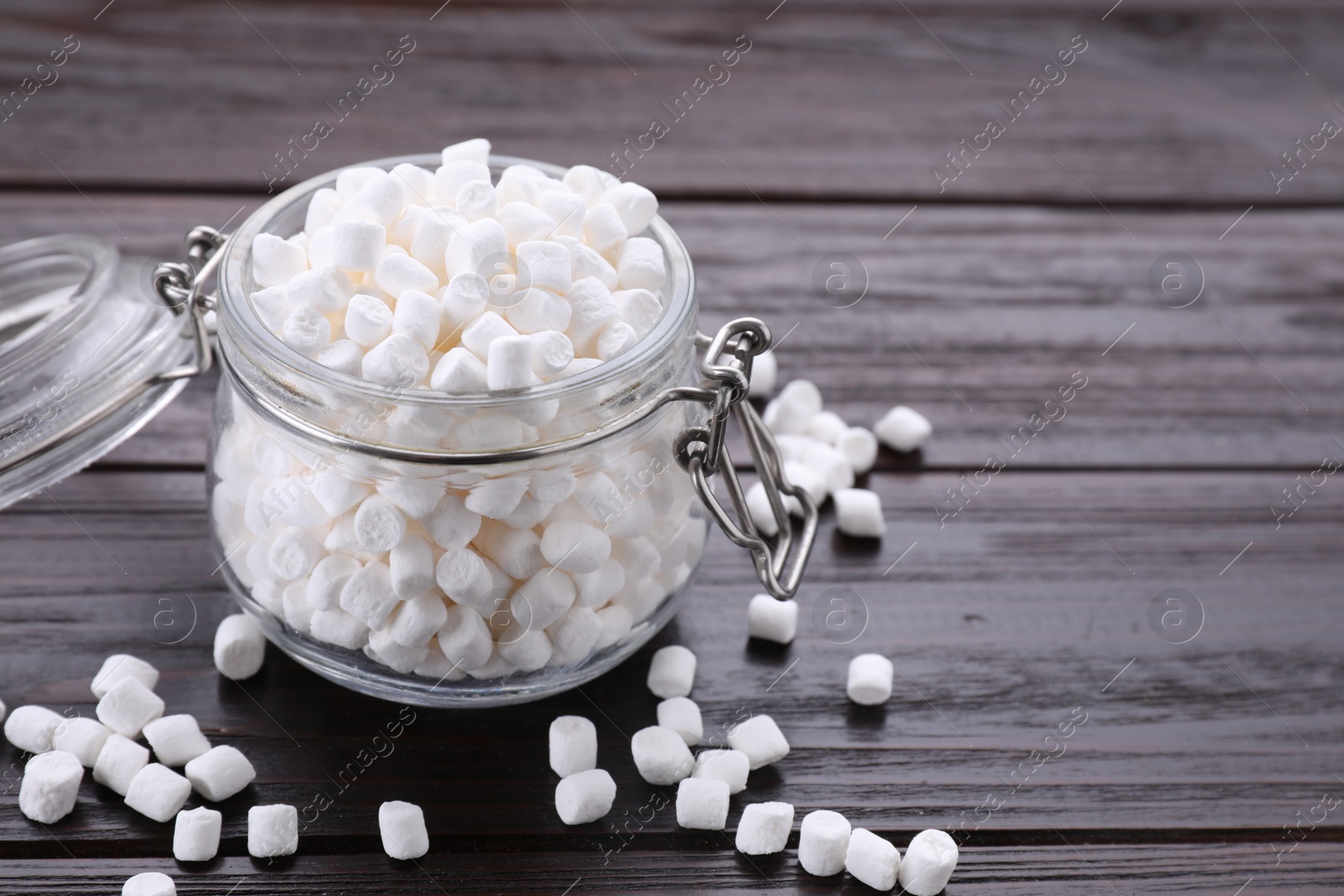 Photo of Glass jar with delicious marshmallows on wooden table, closeup