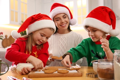 Mother and her cute little children decorating tasty Christmas cookies at table in kitchen