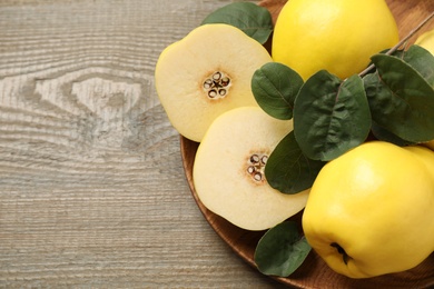 Photo of Fresh ripe organic quinces with leaves on wooden table, top view. Space for text