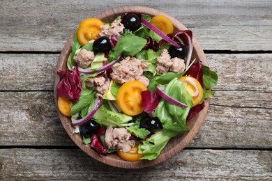 Photo of Bowl of delicious salad with canned tuna and vegetables on wooden table, top view