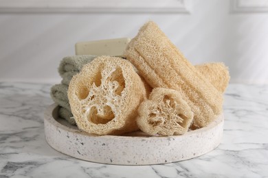 Photo of Loofah sponges, towels and soap on white marble table