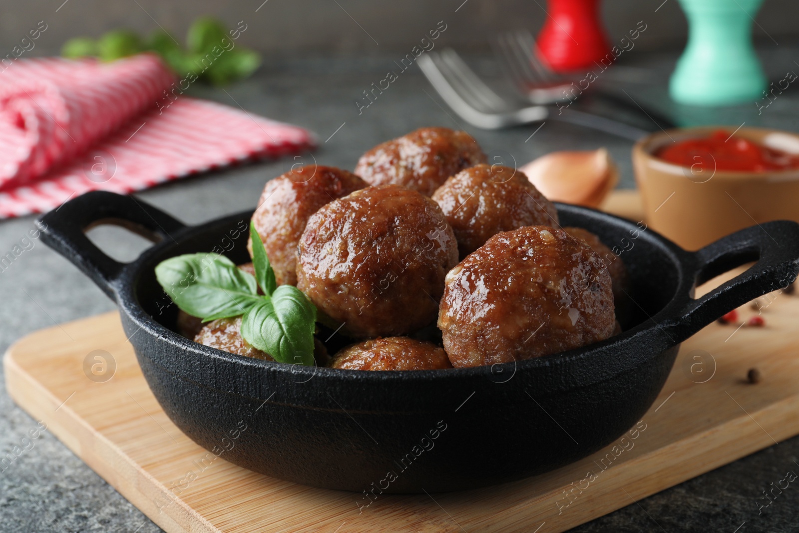 Photo of Tasty cooked meatballs with basil on grey table, closeup