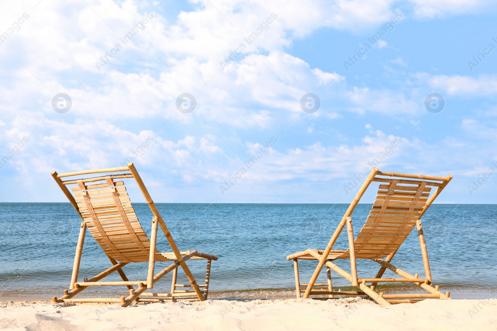 Photo of Sandy beach with empty wooden sunbeds on sunny day