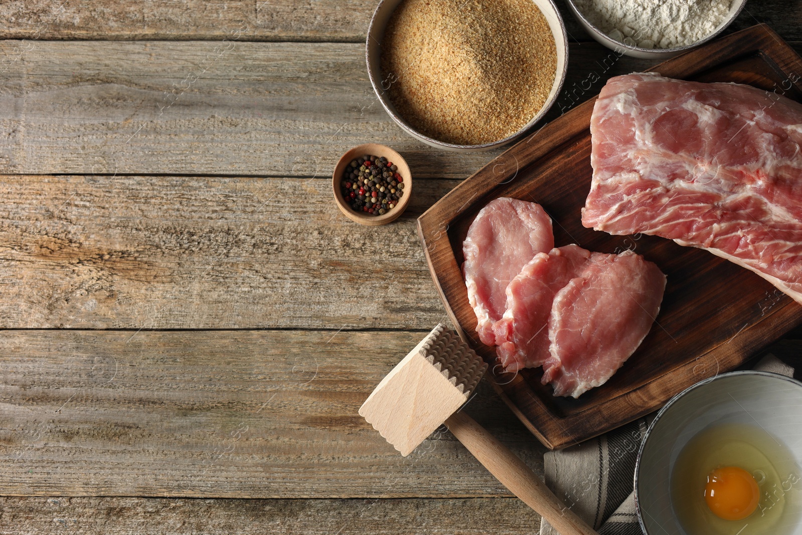 Photo of Different ingredients for cooking schnitzel on wooden table, flat lay. Space for text