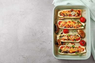 Flat lay composition with delicious stuffed zucchini on light grey table. Space for text