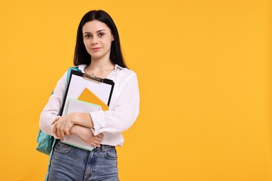 Photo of Student with notebooks and clipboard on yellow background. Space for text