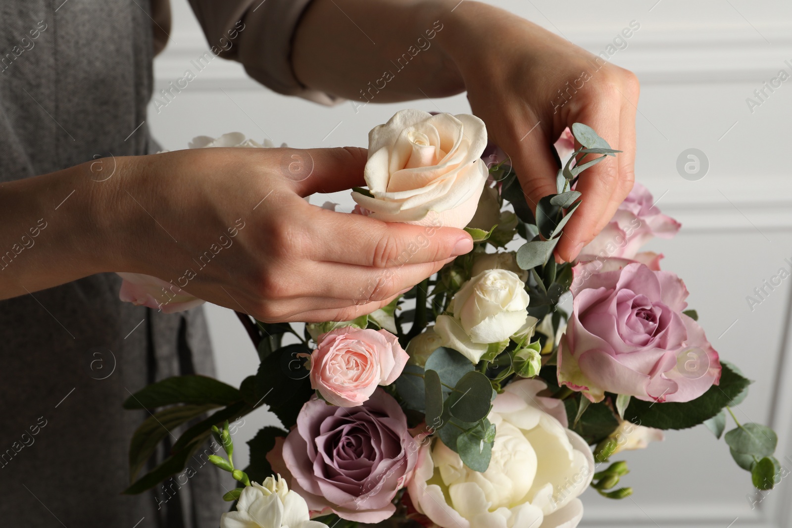 Photo of Florist creating beautiful bouquet with roses indoors, closeup