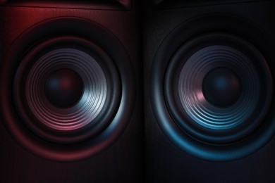 Photo of Modern sound speakers in neon light as background, closeup