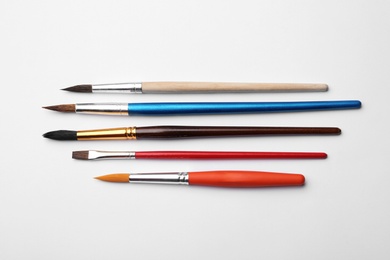 Photo of Different paint brushes on white background, top view