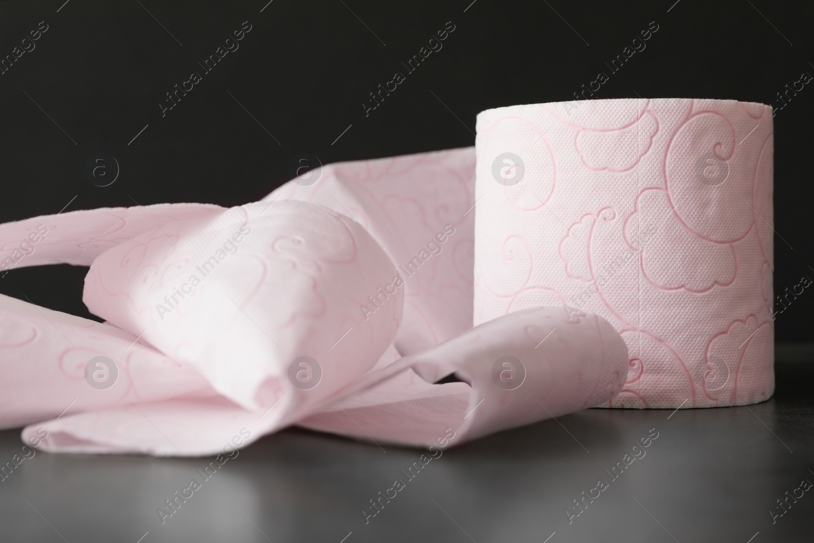 Photo of Soft toilet paper roll on black background