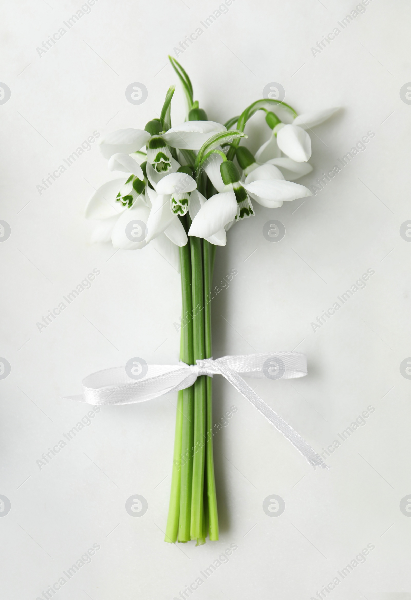 Photo of Beautiful bouquet of snowdrops on light table, top view