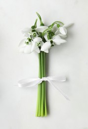 Beautiful bouquet of snowdrops on light table, top view