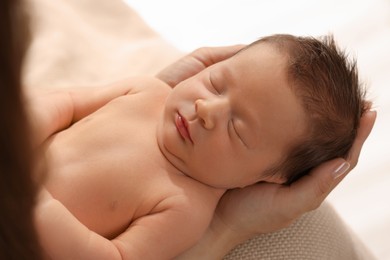 Mother holding her cute newborn baby indoors, closeup