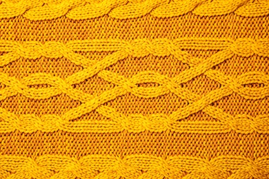 Photo of Soft orange knitted plaid as background, top view