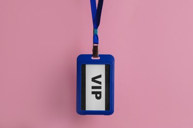 Photo of Plastic vip badge hanging on pale pink background