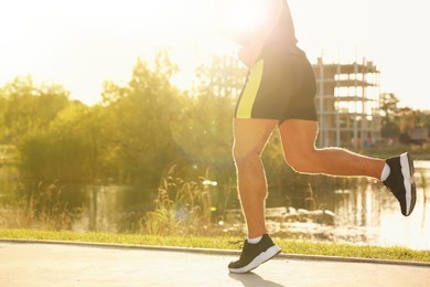 Photo of Man running near pond in park, closeup. Space for text