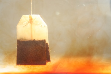 Photo of Brewing tea with bag in hot water, closeup. Space for text