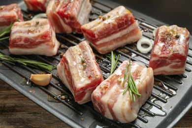 Grill pan with raw ribs and seasonings on table, closeup