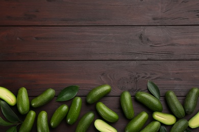 Photo of Fresh seedless avocados with green leaves on wooden table, flat lay. Space for text