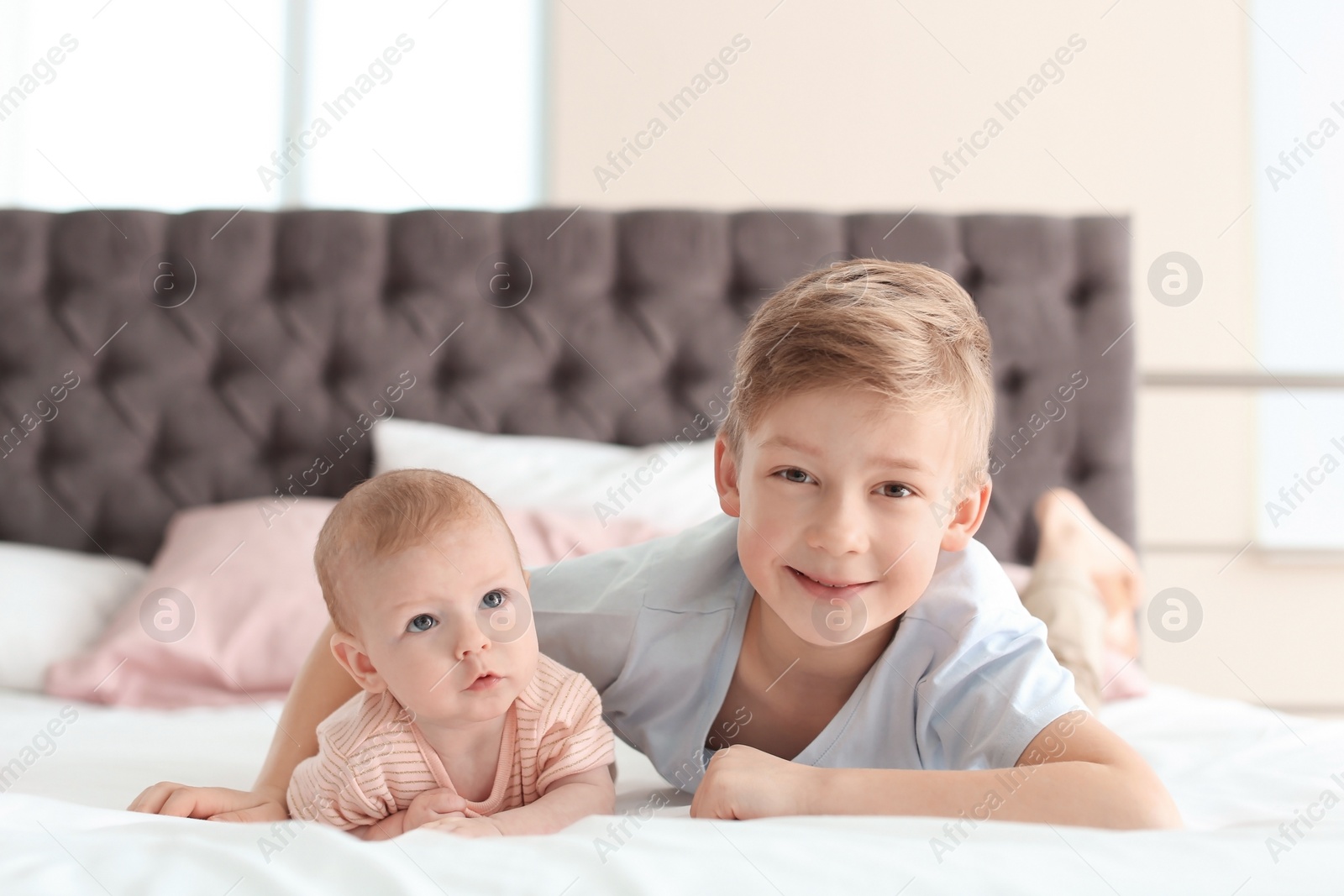 Photo of Cute little baby with elder brother lying on bed at home