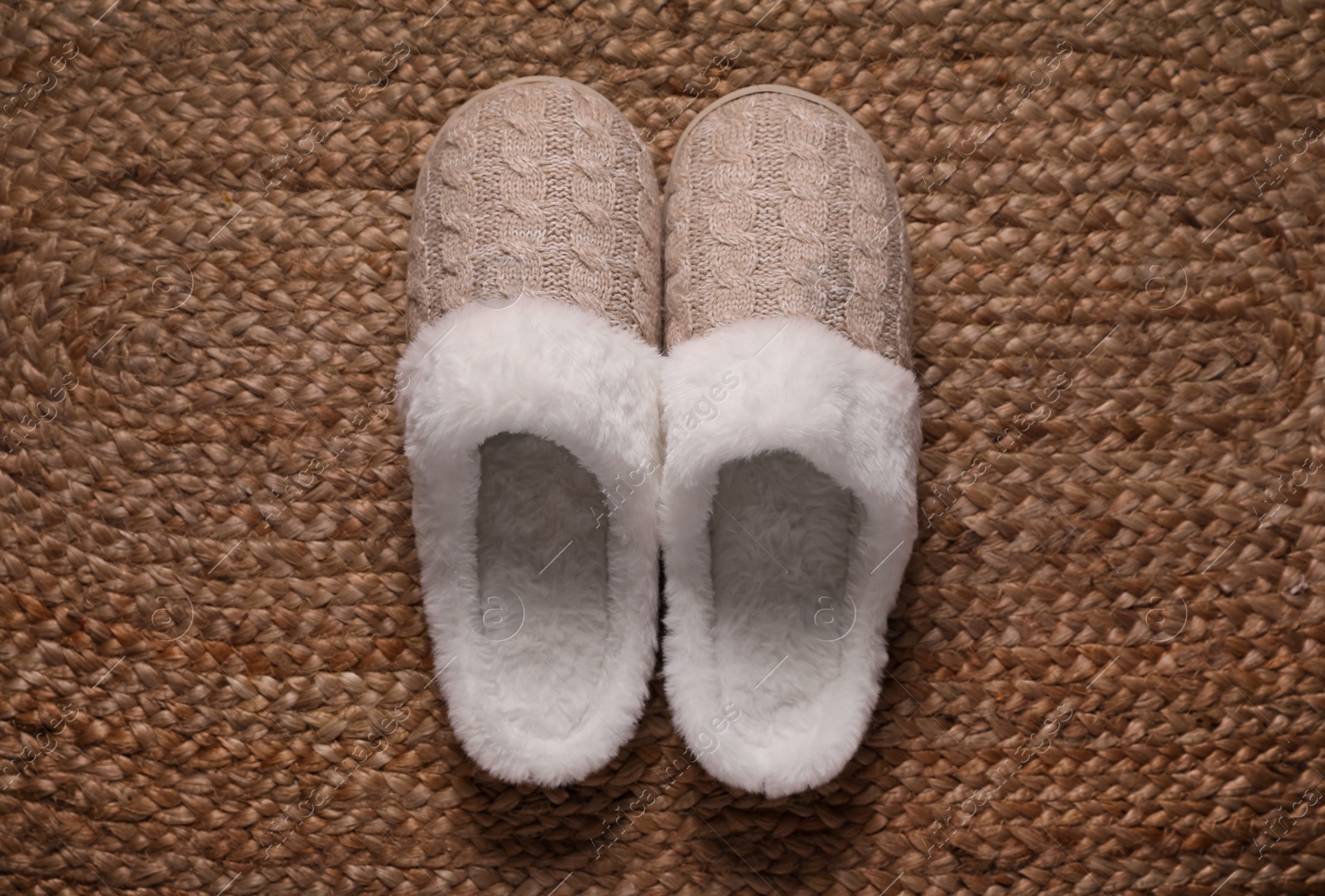 Photo of Pair of beautiful soft slippers on wicker carpet, top view