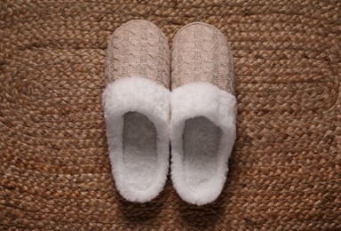 Pair of beautiful soft slippers on wicker carpet, top view