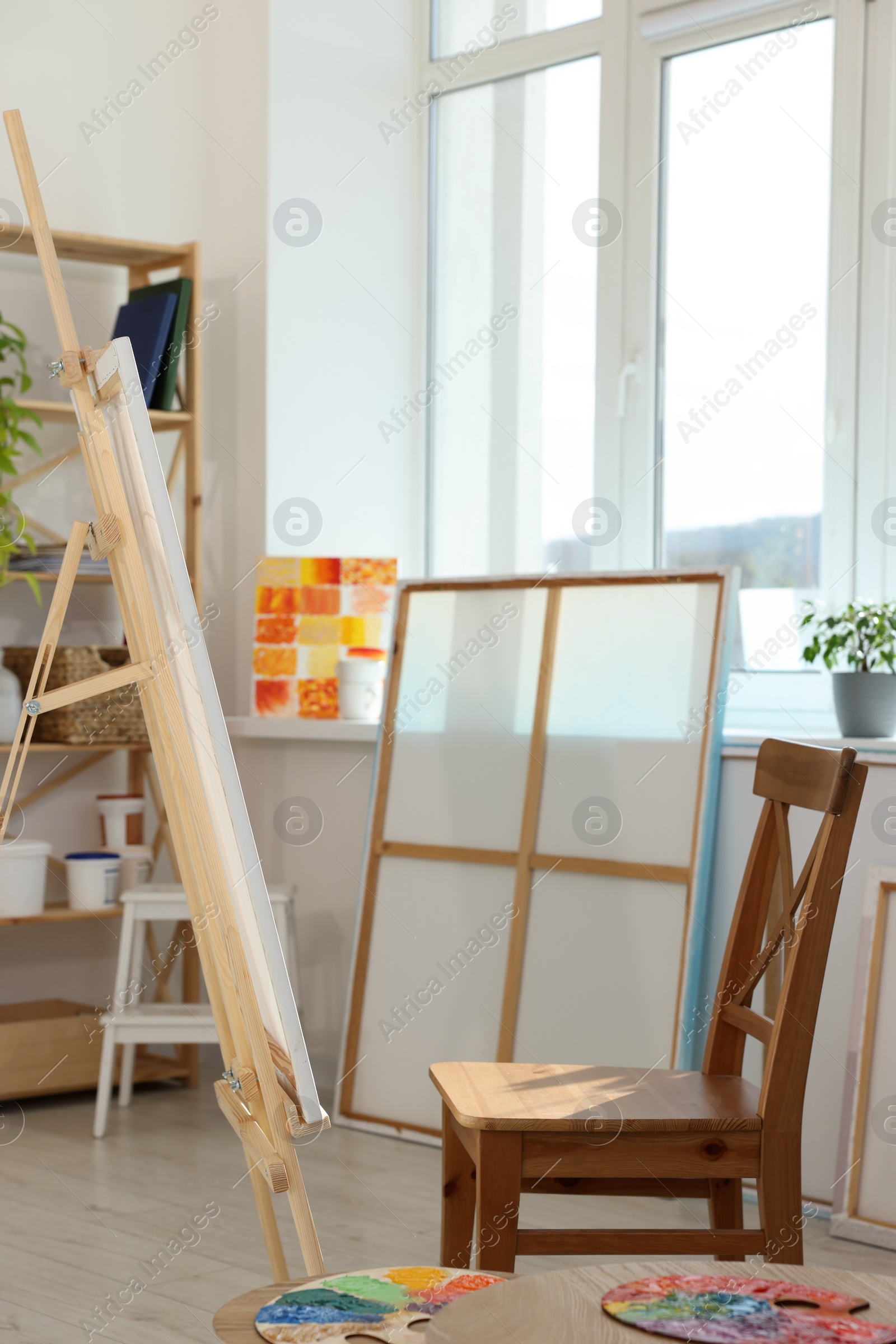 Photo of Easel with canvas and chair near window in artist's studio. Creative hobby